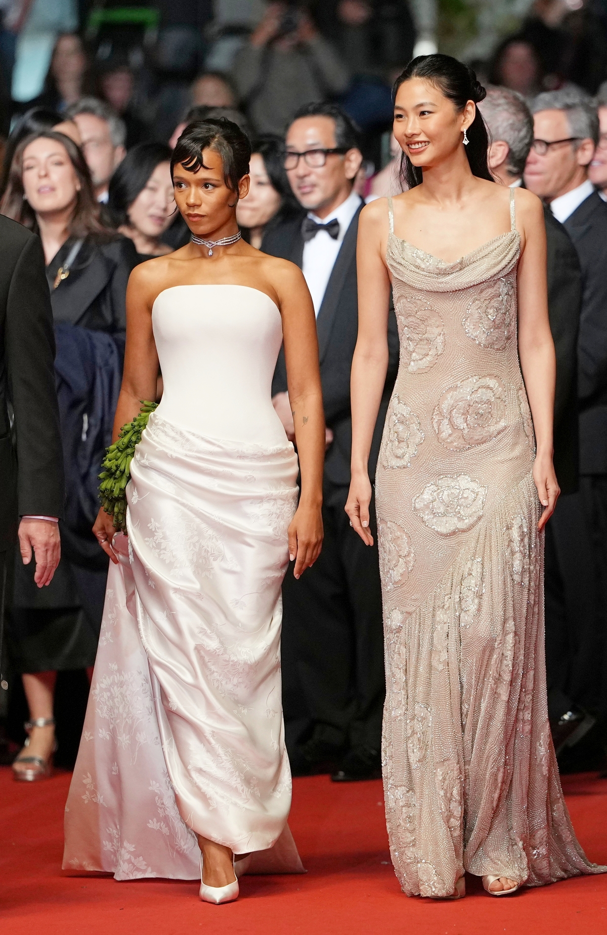 Diễn viên Taylor Russell (trái) ghi điểm bằng đầm Haute Couture của Dior được thiết kế riêng. Bộ váy cúp ngực màu trắng mang họa tiết thêu shibori passementerie, nhấn vào phần hông tạo khối. Theo Elle, shibori passementerie là kỹ thuật thủ công cao cấp kết hợp giữa nghệ thuật nhuộm vải truyền thống Shibori lâu đời của Nhật Bản và nghệ thuật đính kết, tết nơ, bện dây trang trí (passementerie) của phương Tây. Phương pháp này thường được ứng dụng trong các thiết kế thời trang Haute Couture. Ảnh: AP