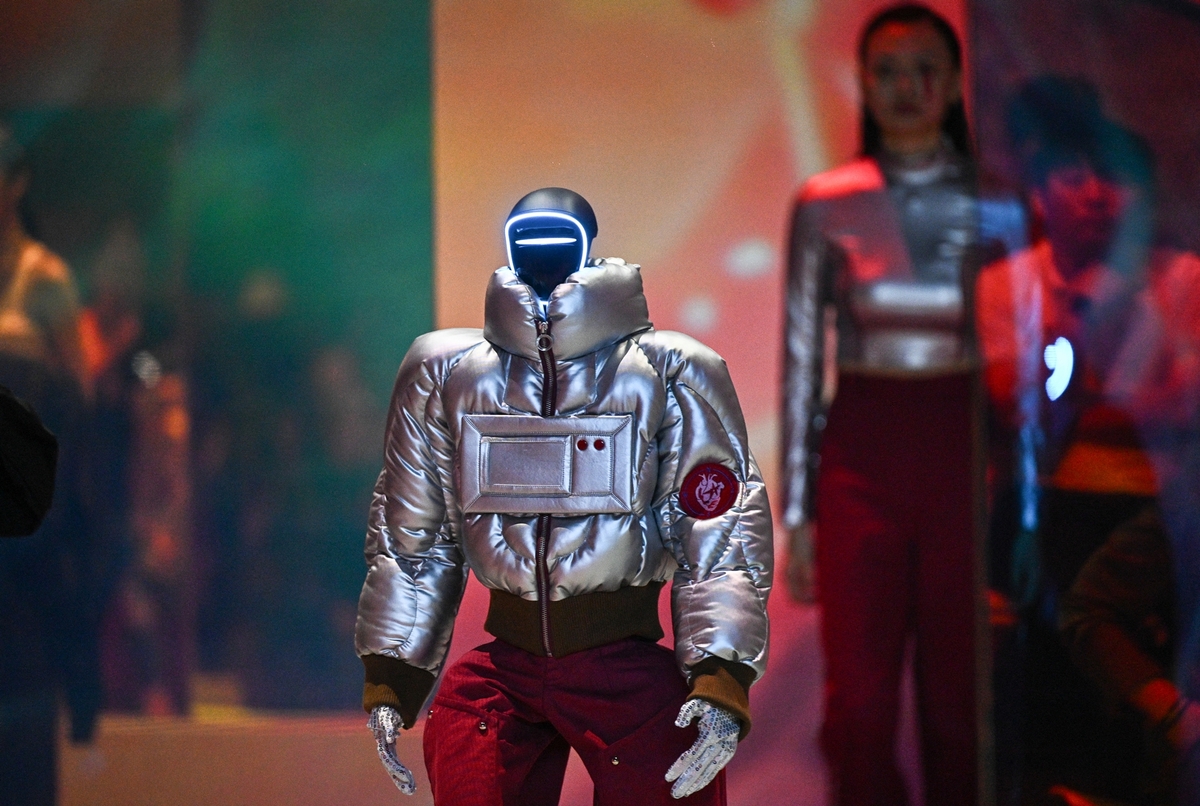Robot mặc áo khoác catwalk phía trước, sau đó là các người mẫu nữ diện thiết kế màu bạc đồng điệu. Ảnh: AFP