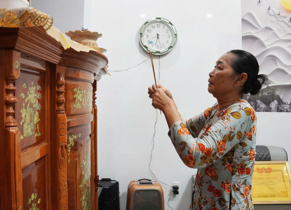 Bà Lê Thị Mừng thắp hương cho mẹ và anh trai. Ảnh: Nam An
