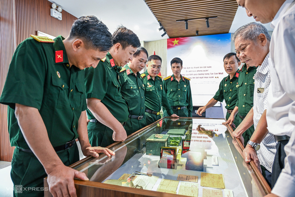 Ông Việt Anh (áo chấm bi) cùng các quân nhân xem hồ sơ, kỷ vật tại trưng bày. Ảnh: Giang Huy