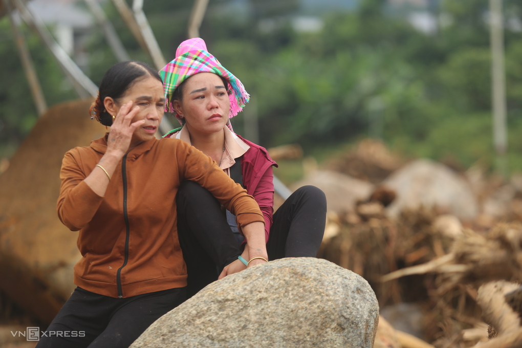 Chị Đường Thị Nhượng (đội khăn) ngồi trên tảng đá ở ngôi nhà bị lũ san phẳng. Ảnh: Gia Chính
