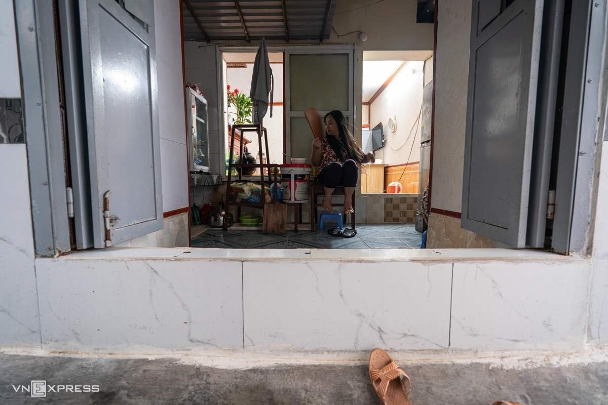 Bà Lê Thị Hon, 62 tuổi, chuyển về khu tập thể Trương Định từ năm 2004, sống tại tầng 1 nhà H4. Hơn 20 năm qua, bà đã chi hơn 20 triệu đồng để sửa chữa căn hộ rộng 13,5 m2. Do nền nhà thấp hơn mặt đường khoảng 20 cm, gia đình phải xây bậc thềm cao ngăn nước mưa tràn vào. "Dù đã nâng thềm, nhiều trận mưa lớn nước vẫn tràn vào nhà", bà Hon nói.