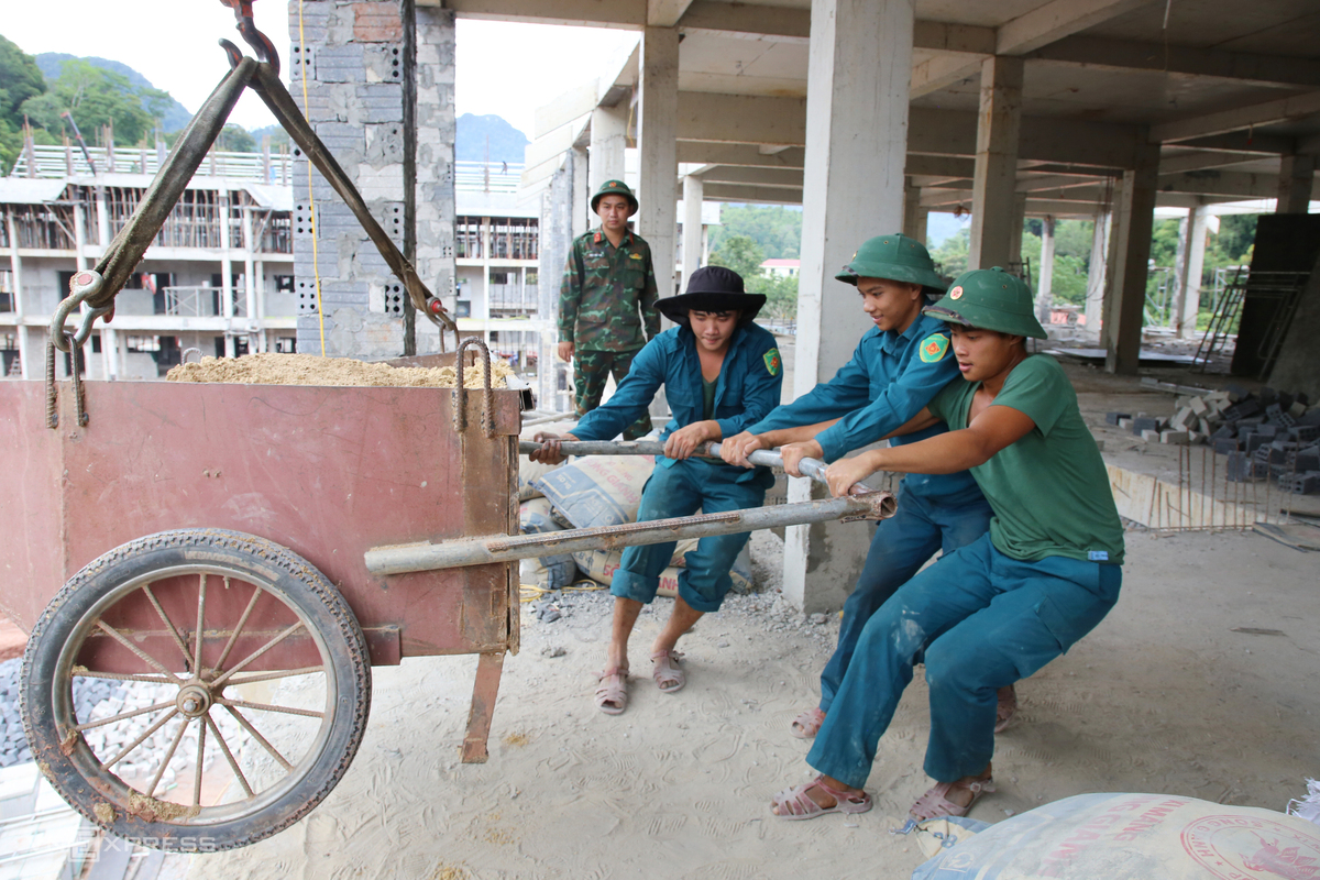Mỗi sáng, bộ đội hành quân gần 300 m đến công trường trước 6h30. Họ đảm nhận những công việc như vận chuyển vật liệu, buộc thép, trộn vữa, san gạt nền.