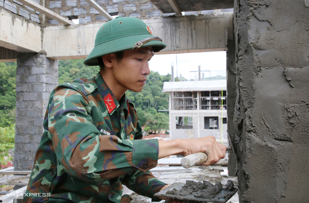 Chiến sĩ Hà Thanh Phong, Trung đoàn Bộ binh 996, cẩn thận trát từng mảng tường. "Dù không phải thợ xây chuyên nghiệp, chúng tôi vẫn cố gắng góp một phần công sức để trường sớm hoàn thành", Phong nói.