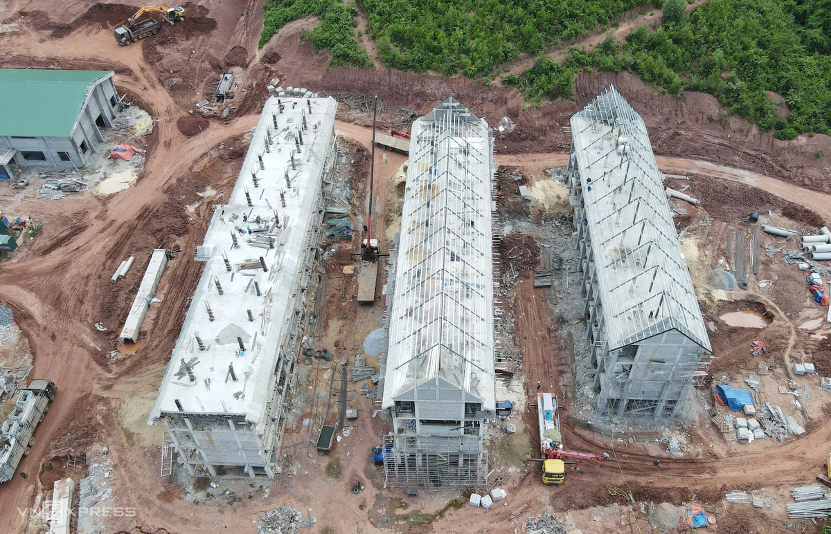 Ba dãy phòng học đã xong phần thô, công nhân đang lợp mái và hoàn thiện các hạng mục còn lại.