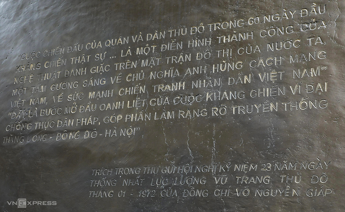 Mặt trước phù điêu khắc họa các chiến sĩ cảm tử quân ôm bom ba càng, hình ảnh biểu tượng cho 60 ngày đêm chiến đấu bảo vệ Thủ đô. Bên cạnh là hình ảnh bộ đội cầm súng, công nhân và phụ nữ Hà Nội sát cánh cùng các chiến sĩ. Phía sau là những mái nhà phố cổ, chợ Đồng Xuân và ô Quan Chưởng xưa. Mặt sau phù điêu khắc đoạn trích trong thư đại tướng Võ Nguyên Giáp gửi Hội nghị kỷ niệm 23 năm Ngày Thống nhất lực lượng vũ trang Thủ đô, tháng 1/1972.